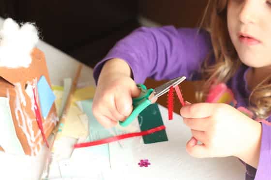 child decorating milk carton for gingerbread village