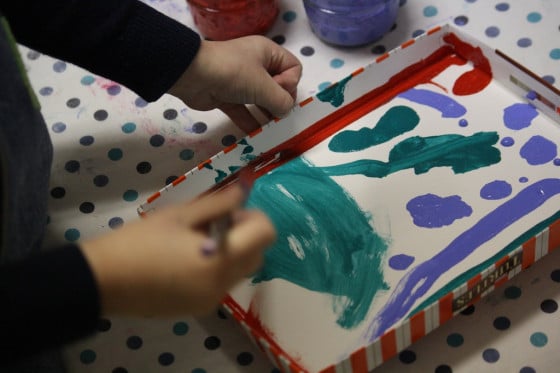 tempera paints, paint brush, box lid, toddler hands