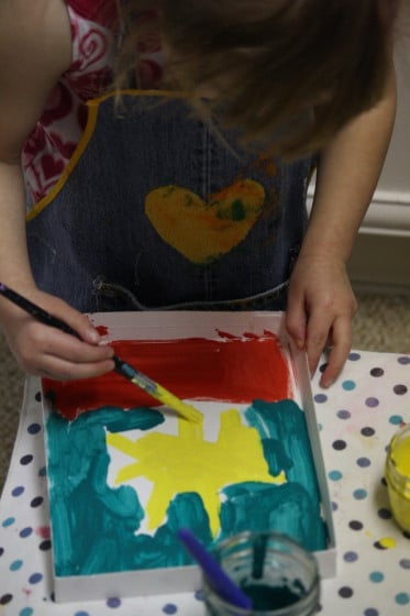 preschooler painting in box lid