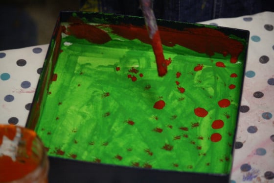 preschooler painting in lid of box