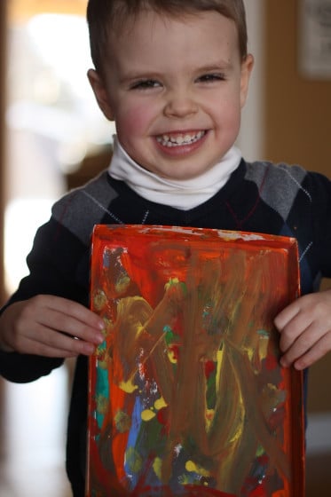 toddler boy holding art painted in box lid