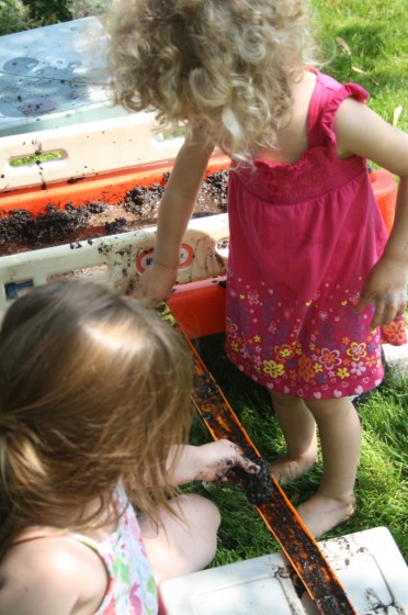 preschool girls driving cars down muddy hot wheels track