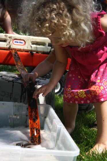 preschooler driving muddy car down hot wheels track into basin of soapy water