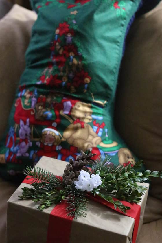 gift wrapped in brown paper in front of Christmas stocking