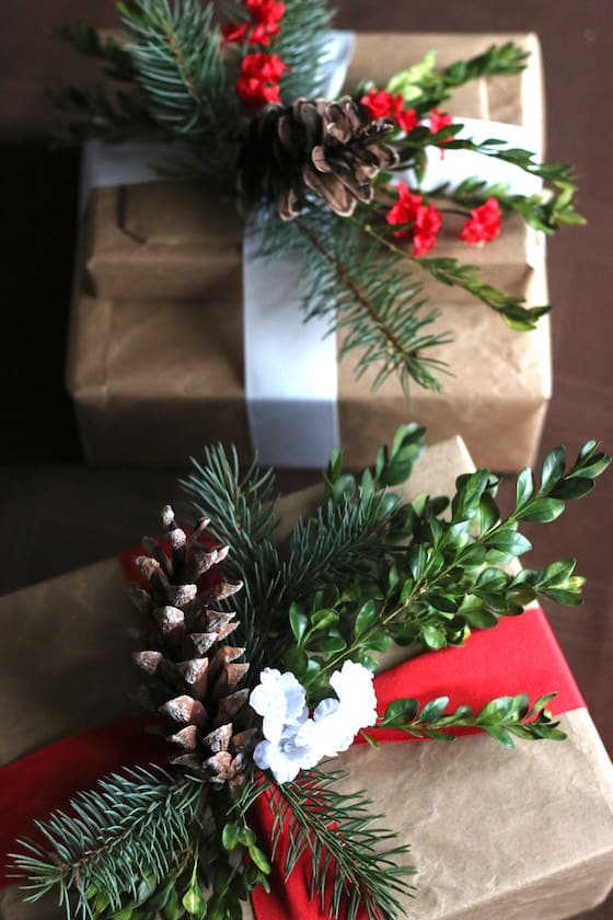 gifts wrapped in brown paper with white ribbon and sprigs of greenery