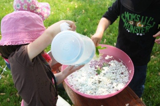 toddlers pouring water into pink bowl