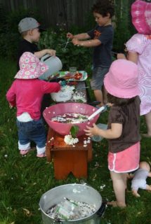 Toddlers and preschoolers gathered around activity bench in backyard