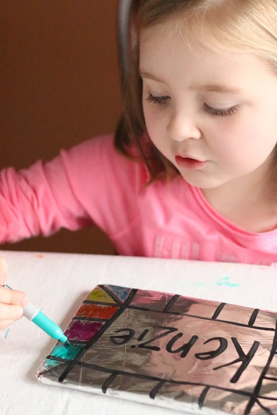 Child colouring her name on tinfoil with sharpie markers