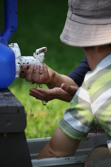 kids washing hands at blue camping water jug