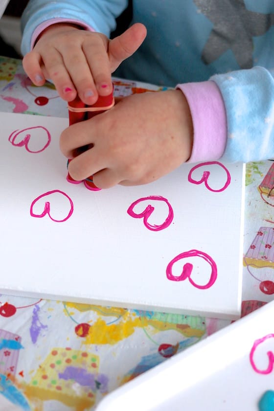 child stamping valentines hearts with toilet paper tube