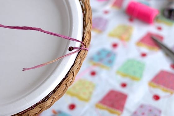 making a bird feeder with a paper plate, wicker paper plate holder and raffia