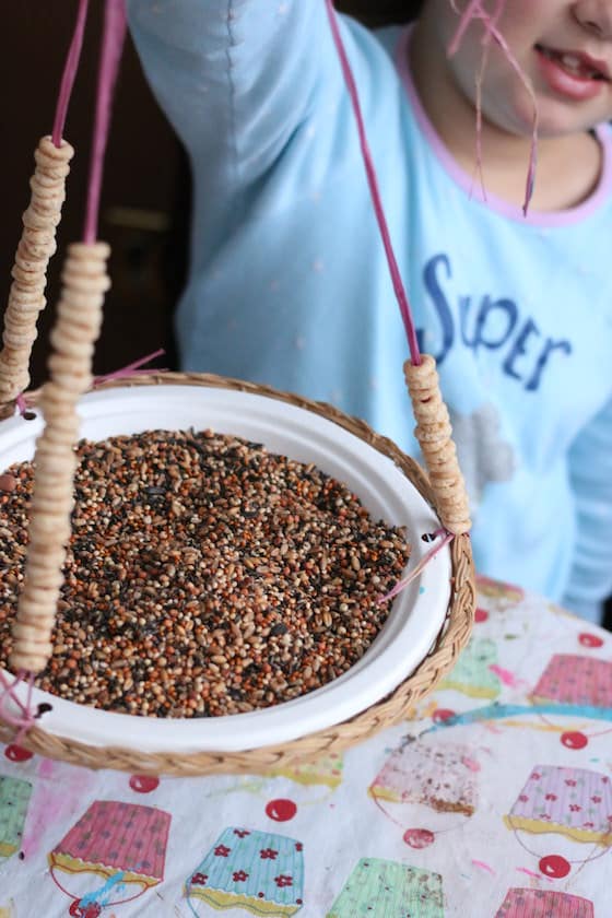 child holding homemade paper plate bird feeder