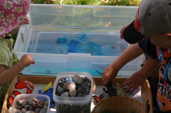 toddlers putting items into ocean sensory bin