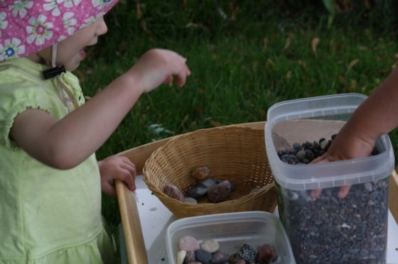 toddler putting rocks in sensory bin