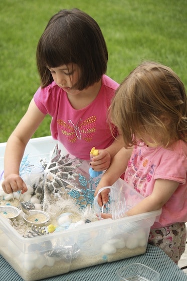 preschooler and toddler with hands in sensory bin