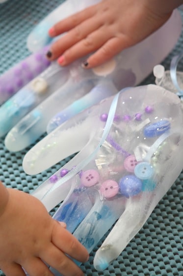 child's hand on frozen gloves filled with water and treasures