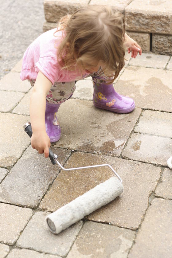 child playing with paint roller and water