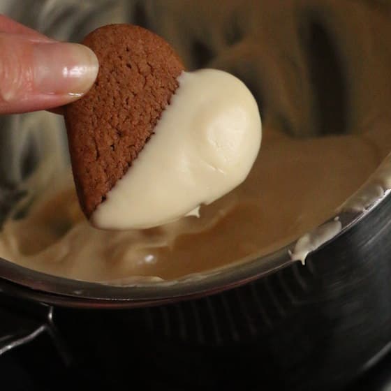 Dipping heart shaped gingerbread cookies in white chocolate