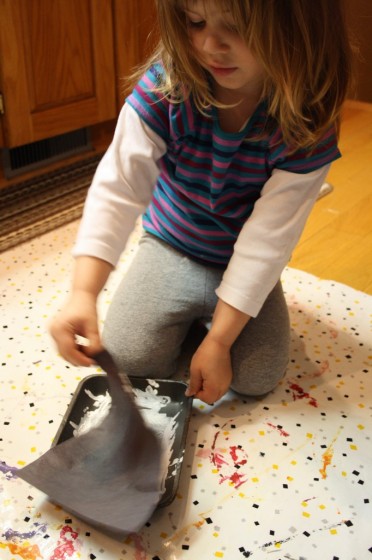 preschooler pressing black construction paper into white paint