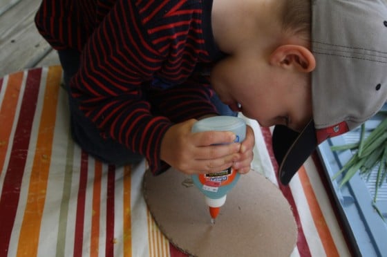 preschool boy squeezing bottle of glue