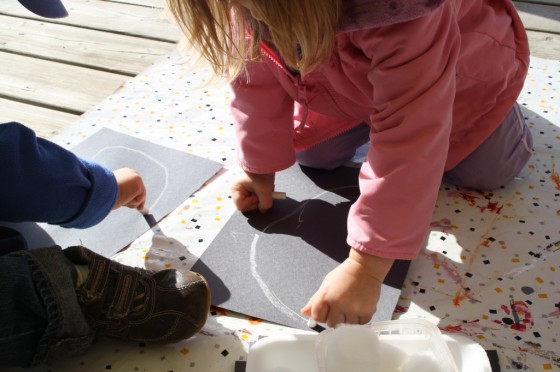 toddler drawing ghost on black construction paper