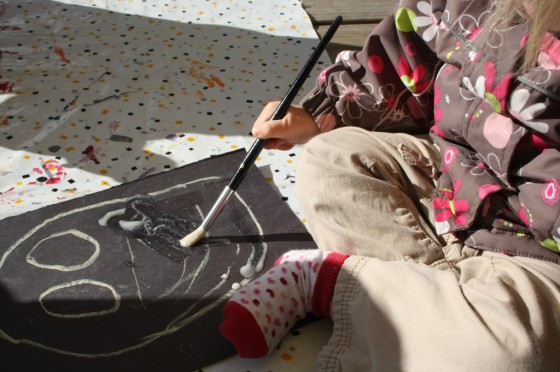 preschooler painting glue on ghost drawn on construction paper