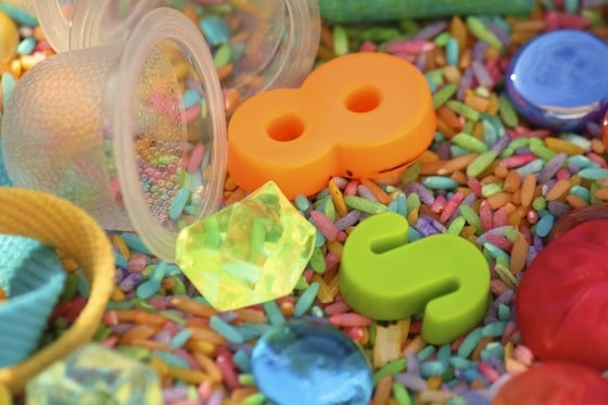 small items and coloured rice in a sensory bin 