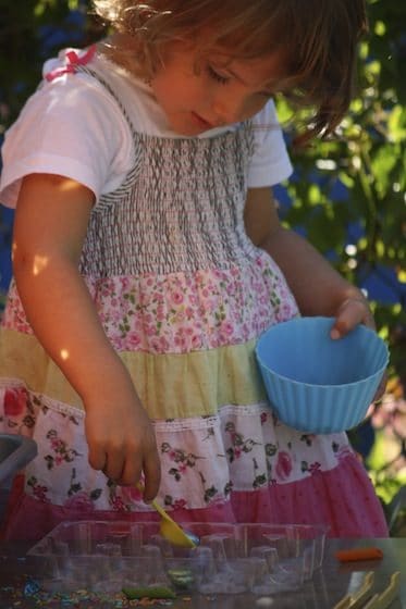 preschooler scooping beads from bowl to tray