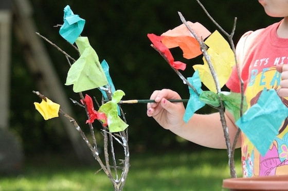 child making a fall tree with twigs and tissue paper