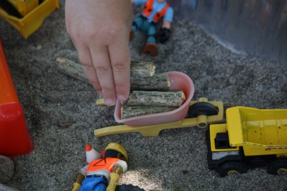 kids stacking sticks in small wheelbarrow