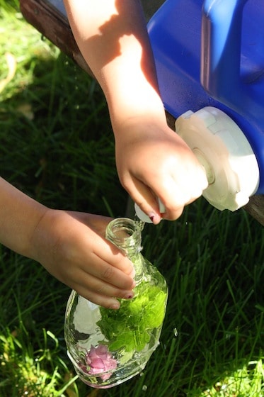 Child filling bottle with water from camping jug