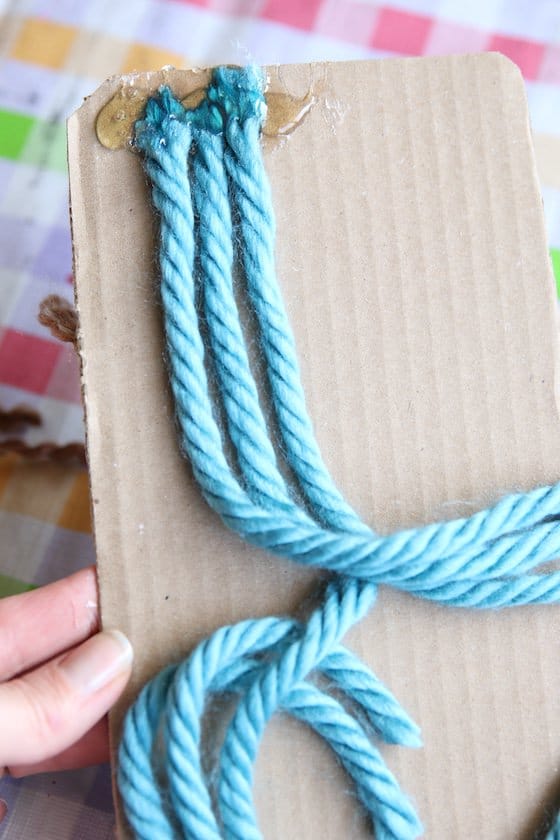 3 strands of blue yarn hot glued to piece of cardboard 