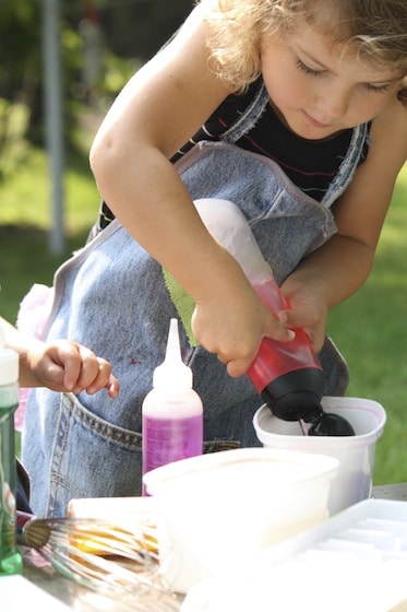 squeezing red water from a shampoo bottle during a science experiment