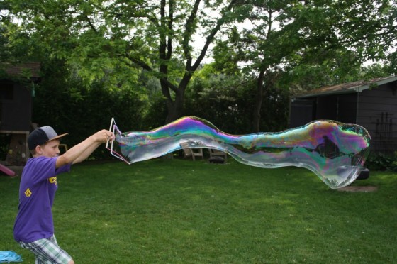 Boy making giant bubbles in the yard with homemade bubble mix