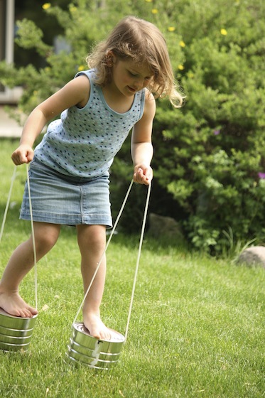 child walking on tin can stilts