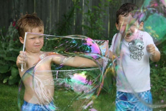 Boys blowing giant homemade bubbles in the yard