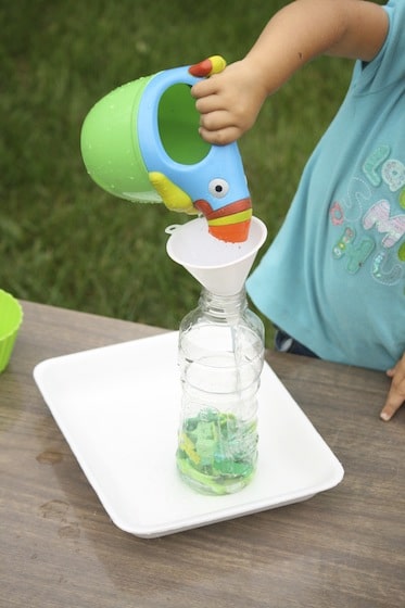 child filling I spy bottle with watering can