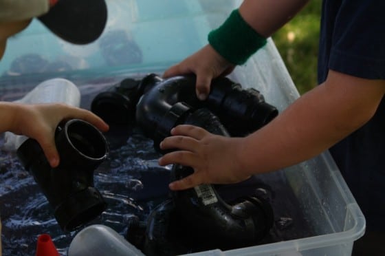 toddlers playing with water and pvc pipes