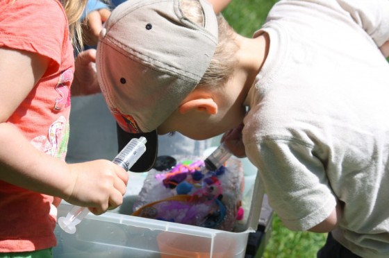 toddler melting block of ice with syringe of water