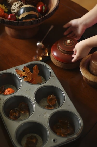 sorting fall items into bowls and a muffin tin at the Fall Sensory Table