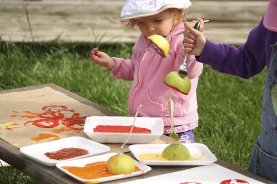 children stamping with forks stuck into apples