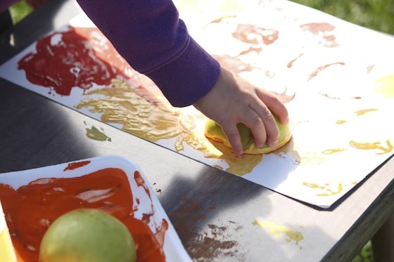 child stamping with apples