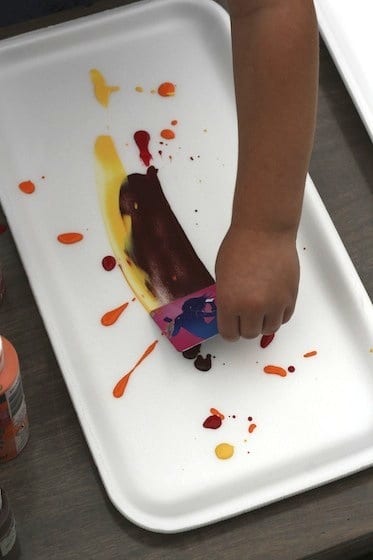 preschooler spreading paint with credit card