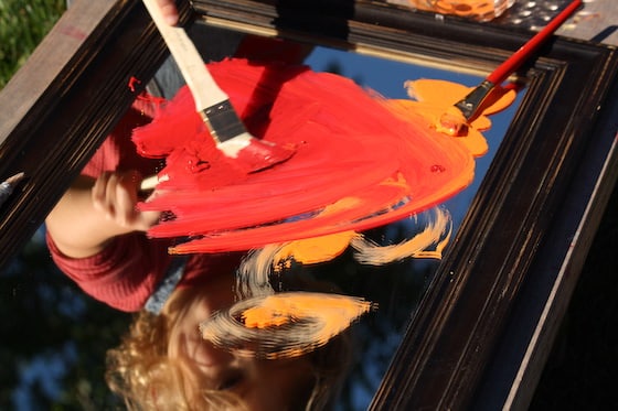 paintbrush and red and orange paint on mirror