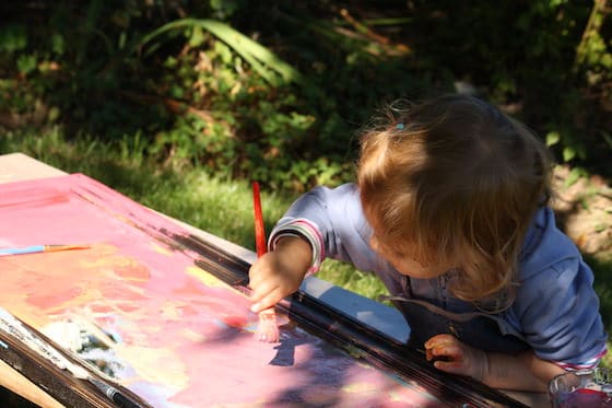 2 year old painting on mirror under tree