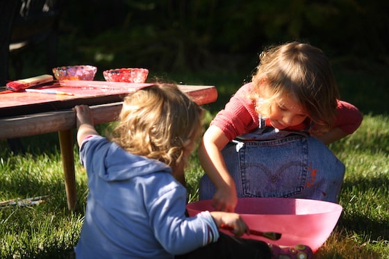 kids washing paintbrushes in bowl of water