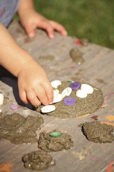 pressing buttons into a mud pie