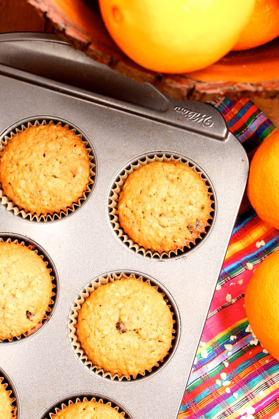 muffins in muffin tin, colourful tablecloth, oranges