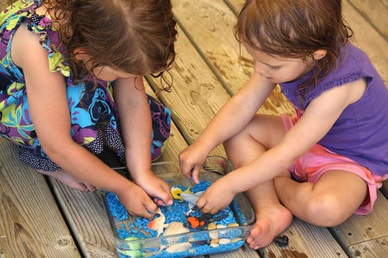 toddler and preschooler playing with small ocean sensory bin