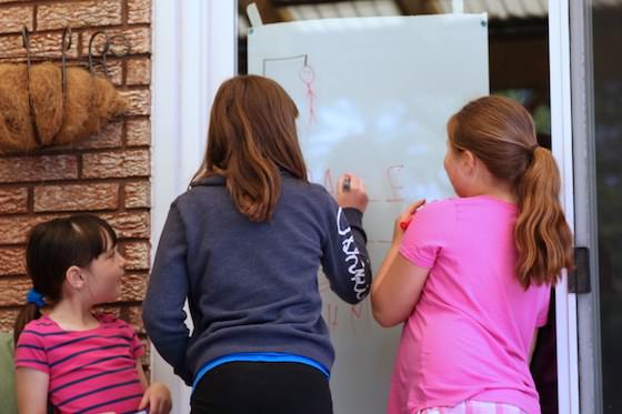 kids playing hangman on patio door with dry erase markers